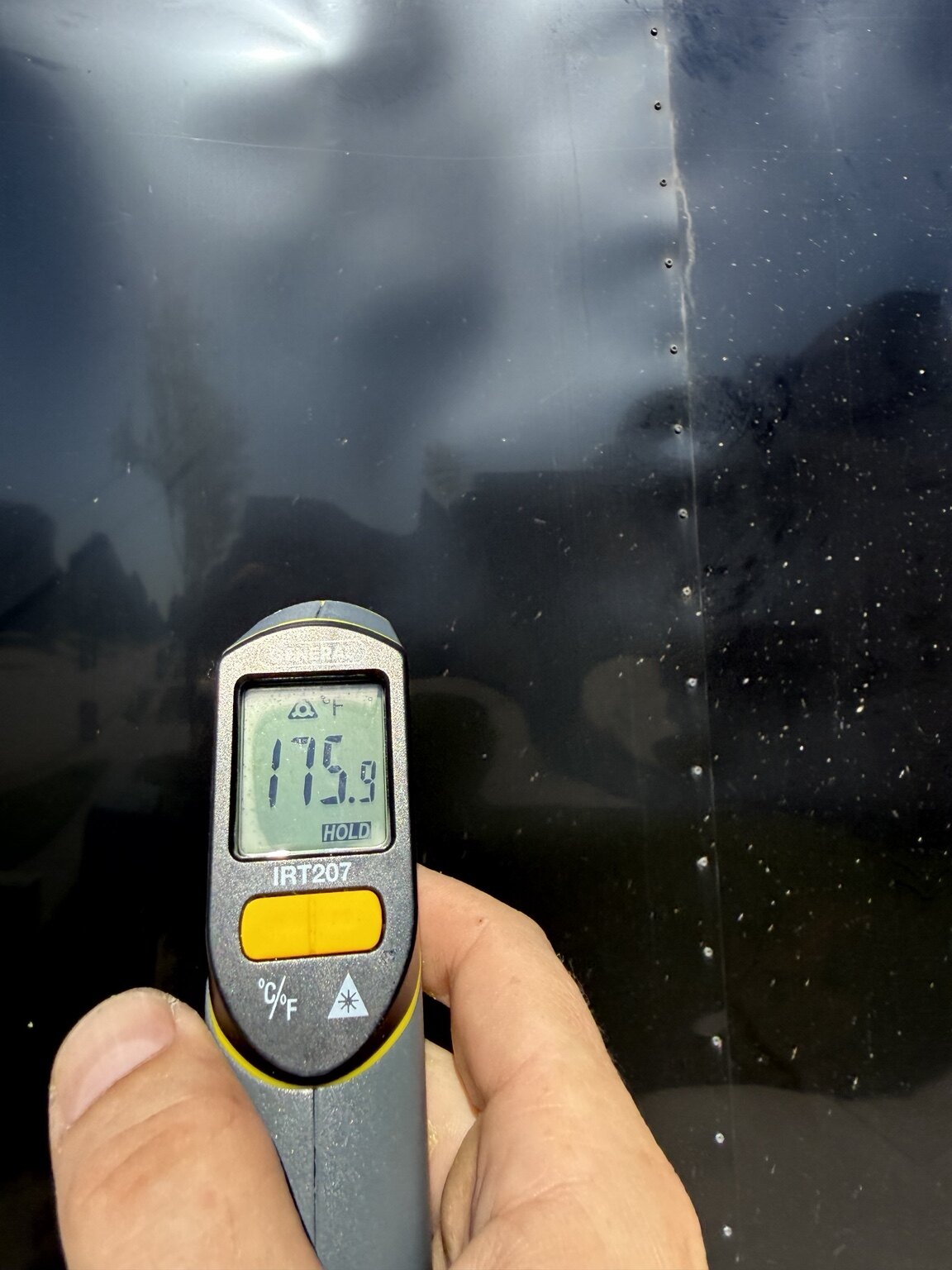 Black Trailer Solar & Off-Grid Conversion Infrared thermometer reading 175.9 degrees Fahrenheit on the black trailer exterior
